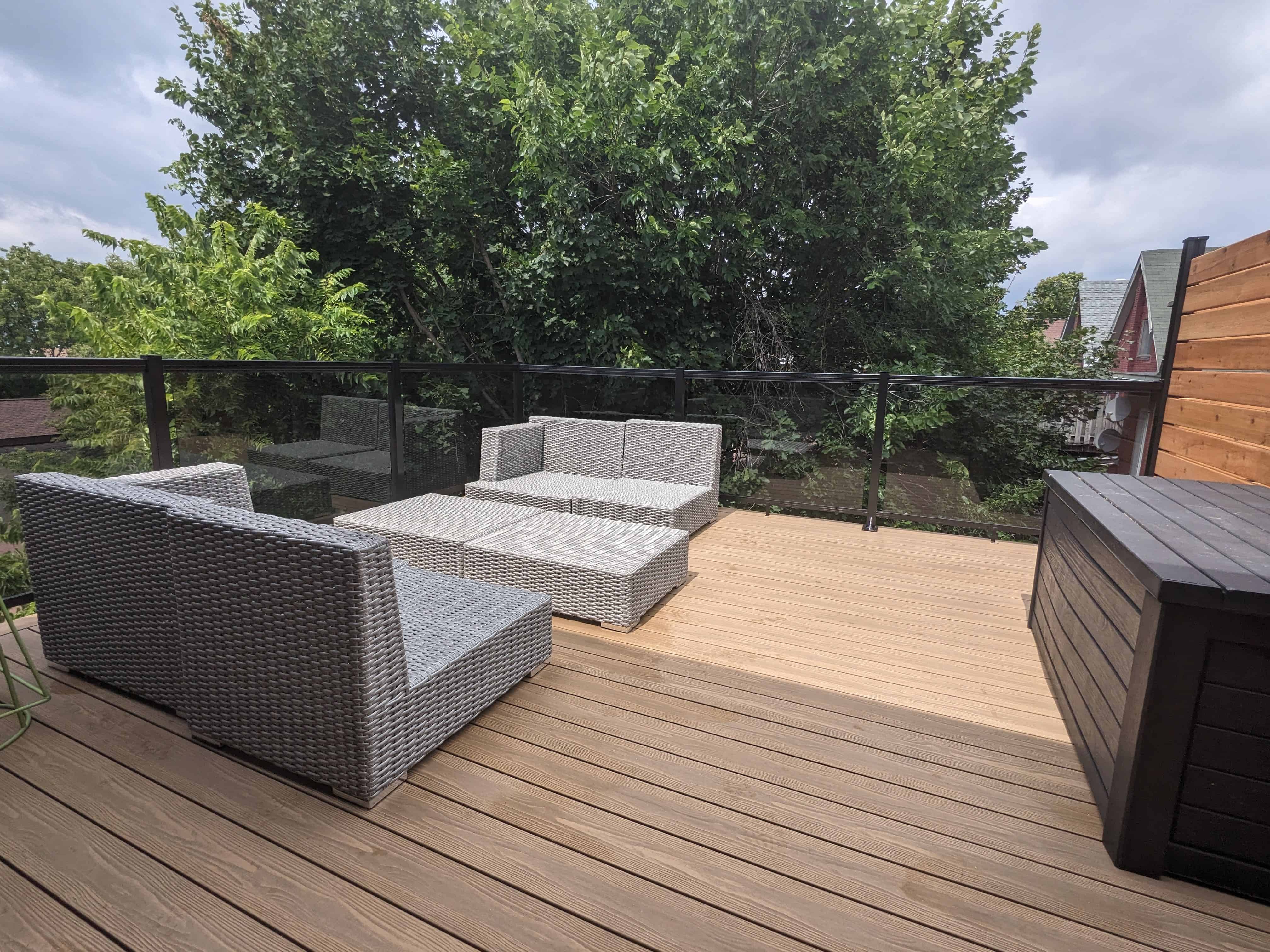 Composite deck with outdoor seating and glass railing in Ottawa